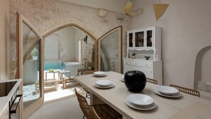 A dining area with a long table, chairs, and a white cabinet with glass doors. - Sutor Chic Manor (Rethymno)