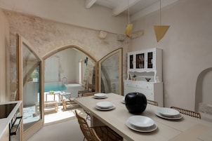 Un comedor con una mesa larga, sillas y un armario blanco con puertas de vidrio.