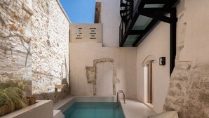 A private pool area with a stone wall, a wooden bench, and a lounge chair. - Sutor Chic Manor (Rethymno)