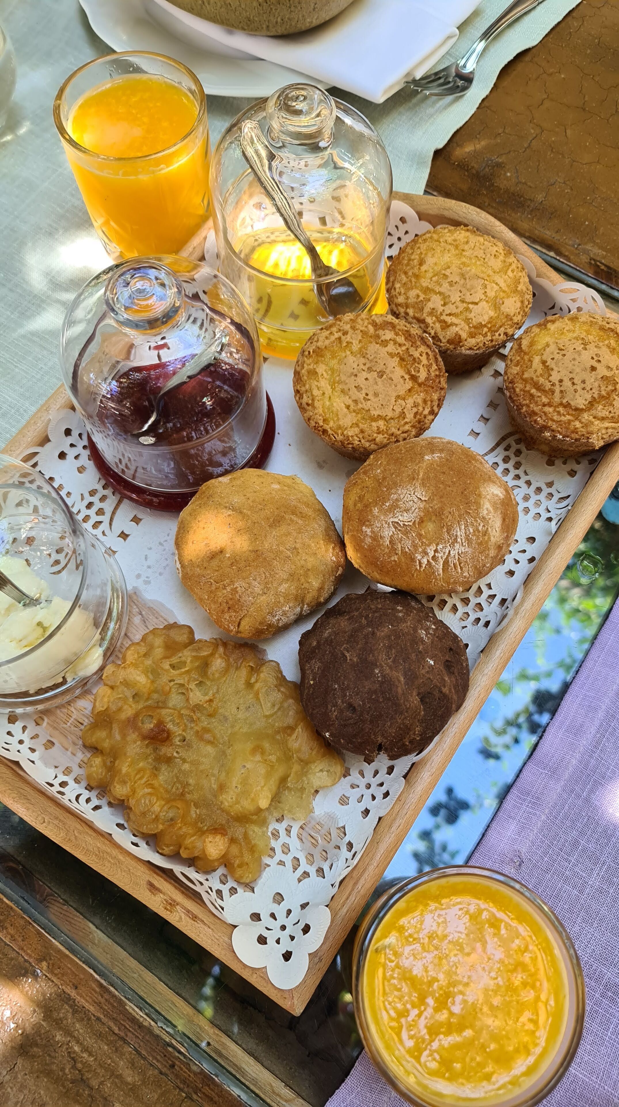 Una bandeja con varios pasteles, un vaso de jugo de naranja y una vela sobre una mesa.