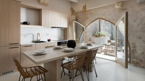 A modern kitchen with a central island, wooden cabinets, and a large window overlooking a garden. - Sutor Chic Manor (Rethymno)
