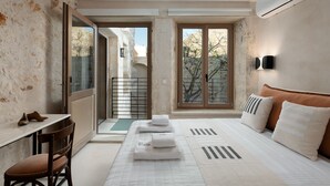 A hotel room with a bed, a desk, a chair, and a view of the outside. - Sutor Chic Manor (Rethymno)