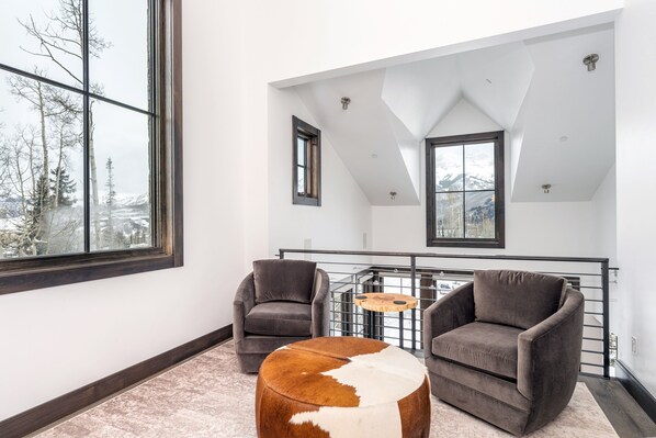 Un salon moderne avec un plafond haut, de grandes fenêtres et une vue sur un paysage enneigé.