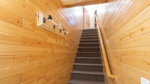 Ein Holzinnenraum mit Teppich und einer Wendeltreppe, die zu einer Tür führt.