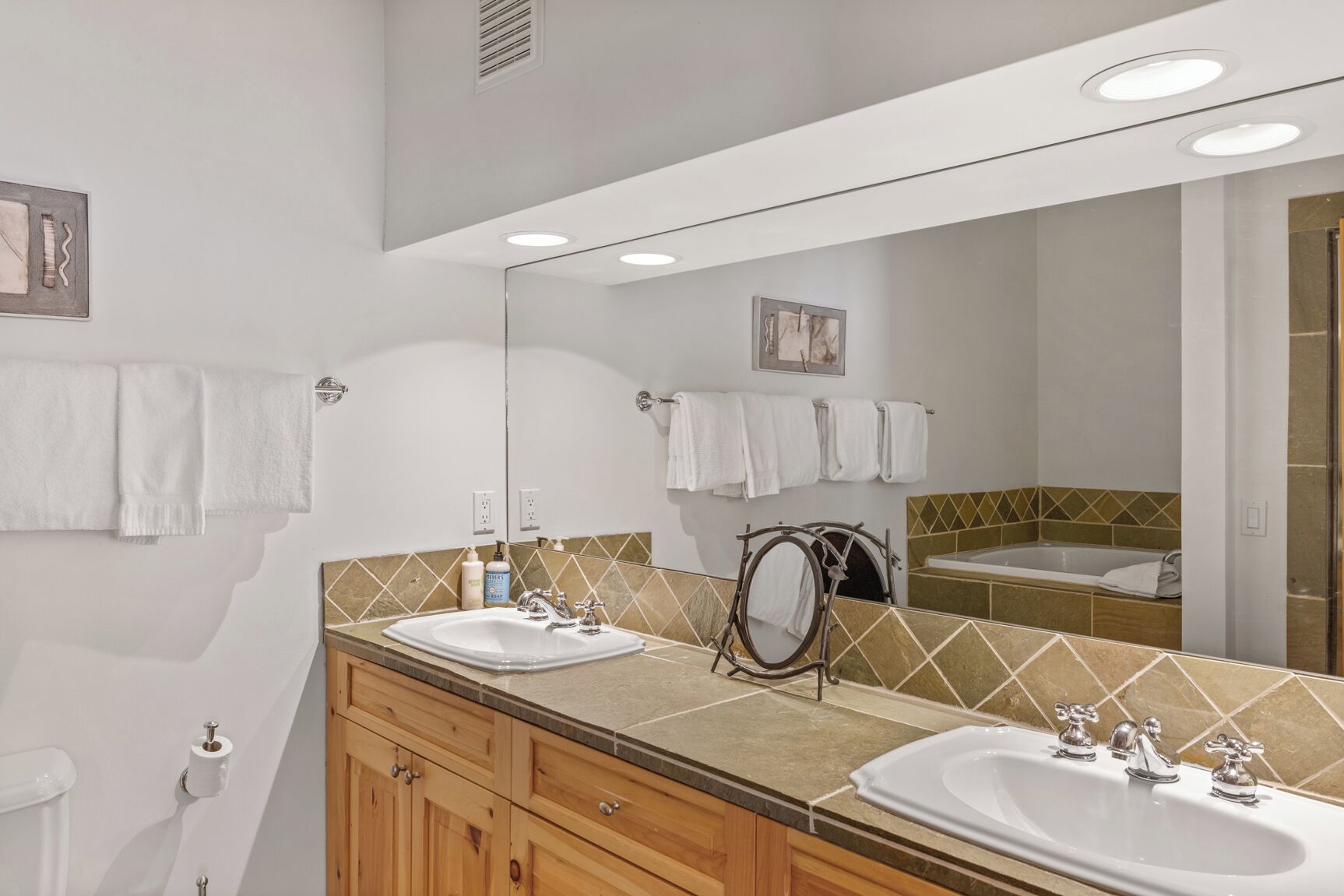 A bathroom with two sinks, a large mirror, and a bathtub.