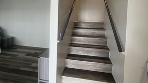 Eine Treppe mit Holzboden und Metallgeländern, die zu einer Zwischenebene mit einer Leuchte führt.