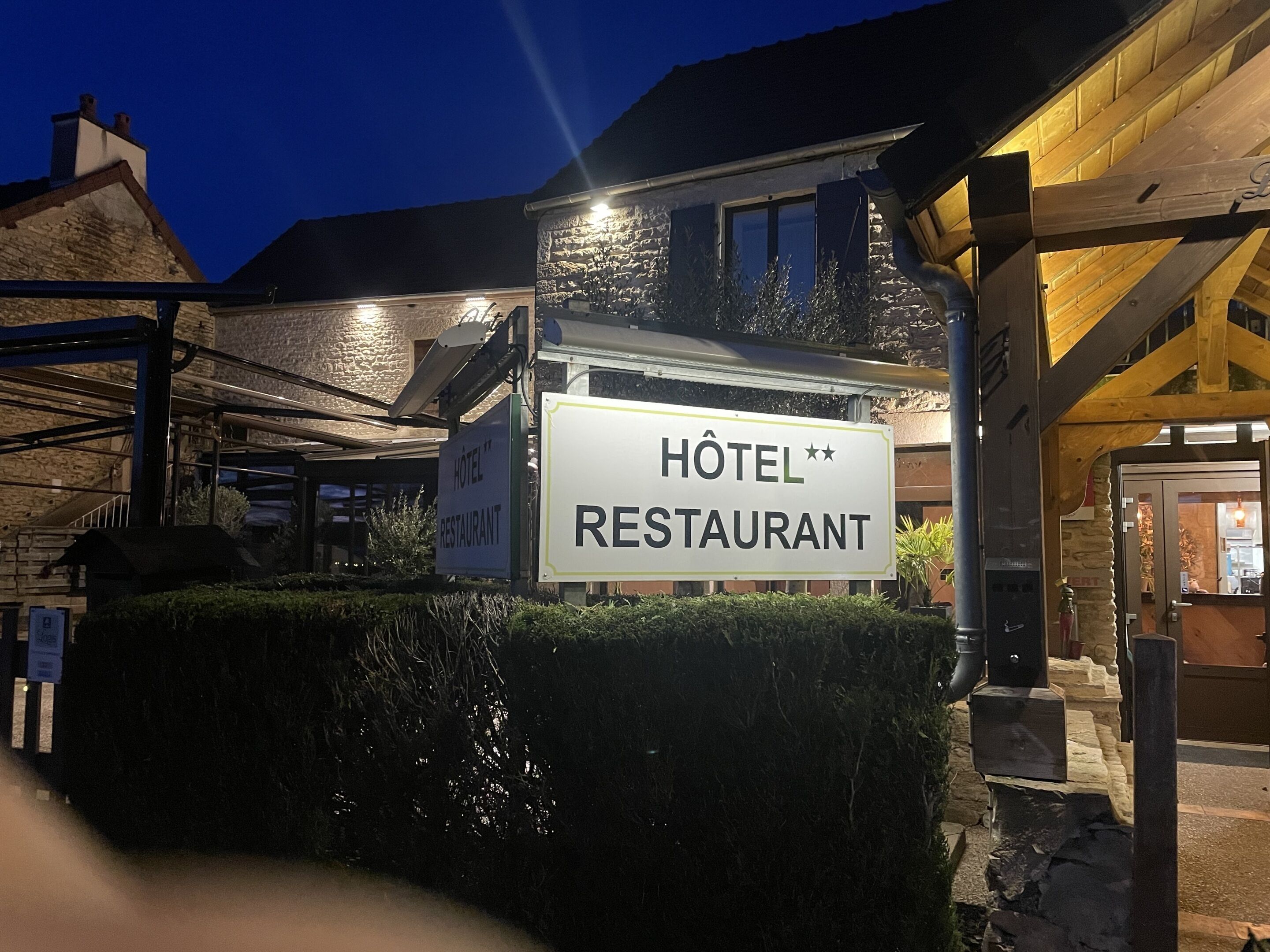 Une enseigne pour un hôtel et un restaurant dotés d’une façade en pierre et de poutres en bois.