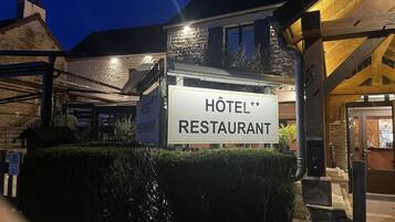Une enseigne pour un hôtel et un restaurant dotés d’une façade en pierre et de poutres en bois.