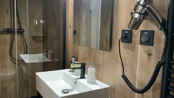 Une salle de bain avec un lavabo blanc, un miroir, un sèche-cheveux et un porte-serviettes.