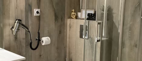 A modern bathroom with a glass-enclosed shower, a white toilet, and a wooden wall.