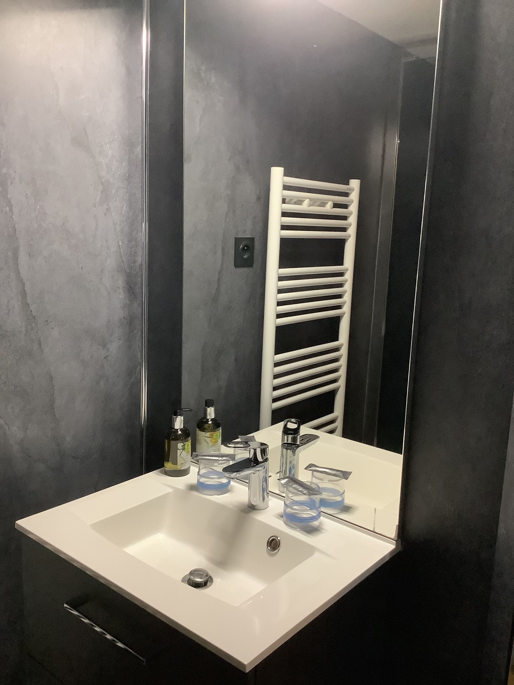 Ein Badezimmer mit einem weißen Waschbecken, einem Spiegel und einem Handtuchhalter.