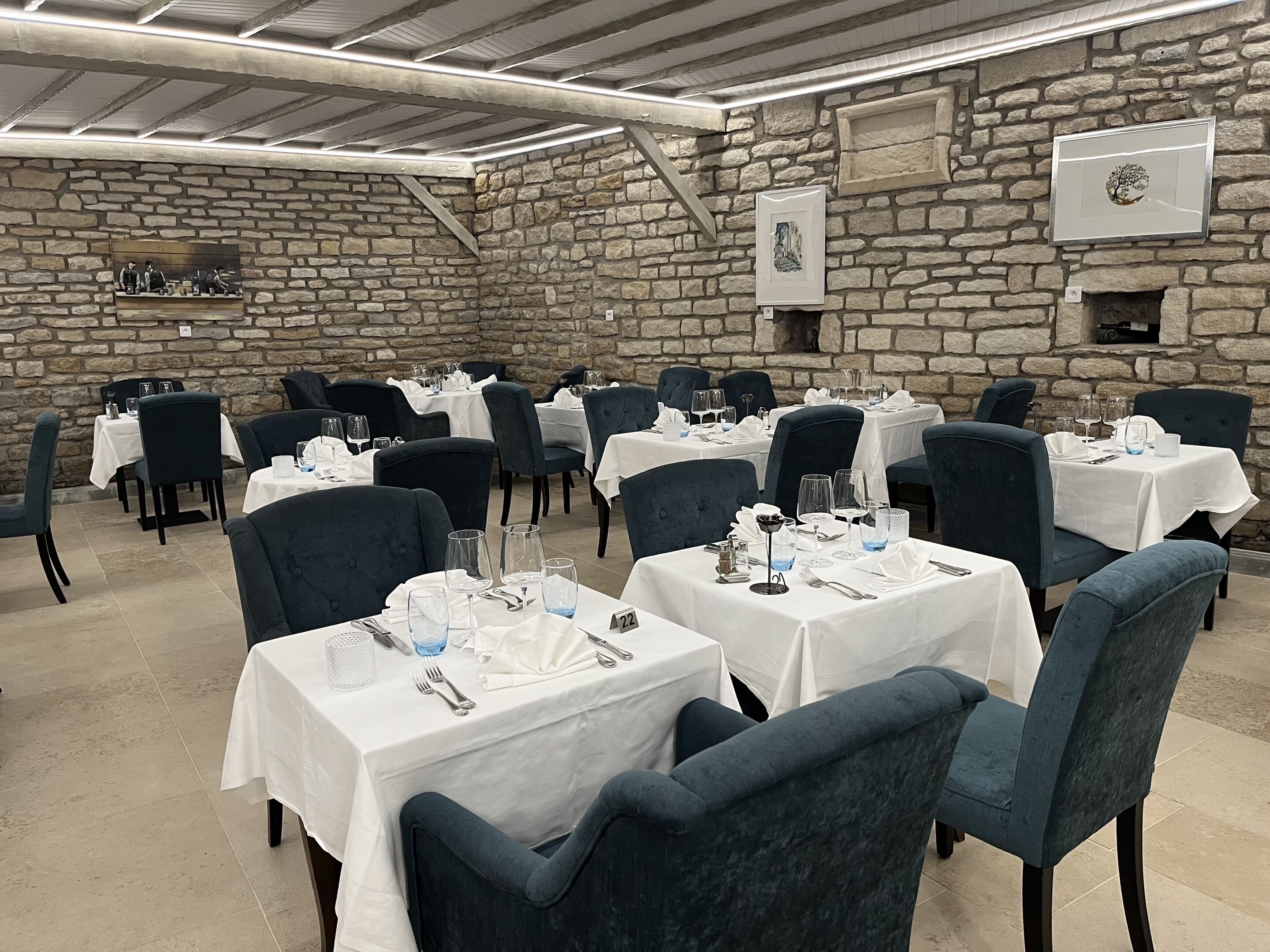 A restaurant with stone walls and multiple tables set for dining.