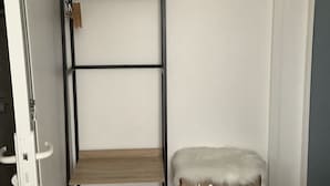 Una habitación con literas, un pequeño banco, un estante de madera y un equipo de aire acondicionado en la pared.