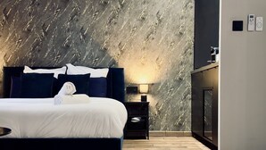 Ein modernes Schlafzimmer mit Wand im Marmoroptik, dunklem Kopfteil, Nachttisch mit Lampe und Holzboden.