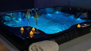 Ein Whirlpool mit Kerzen und Gläsern, ein Handtuch und eine Steuerung.