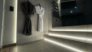 Ein modernes Badezimmer mit einem großen Spiegel, einem Handtuchhalter mit zwei Handtüchern und einer Fußbodenheizung.