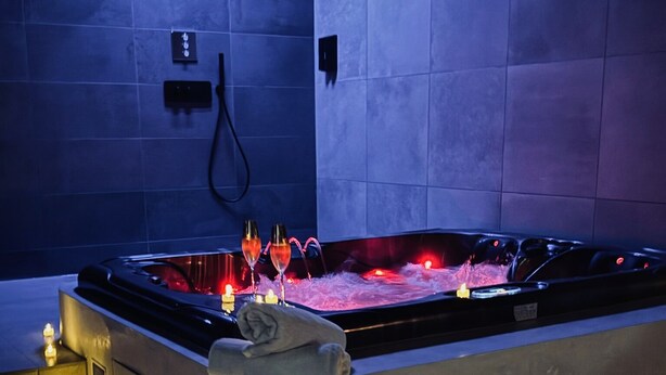Ein modernes Spa mit einer beheizten Steinbadewanne, Kerzen und einem Handtuch am Rand.