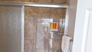 Une douche avec une porte en verre, des toilettes et un porte-serviettes.