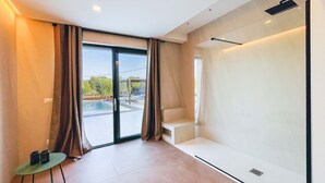 Ein modernes Zimmer mit einer Schiebeglastür, die zu einem Poolbereich führt, einem kleinen Tisch mit einem Stuhl und einer integrierten Sitzbank an der Wand.