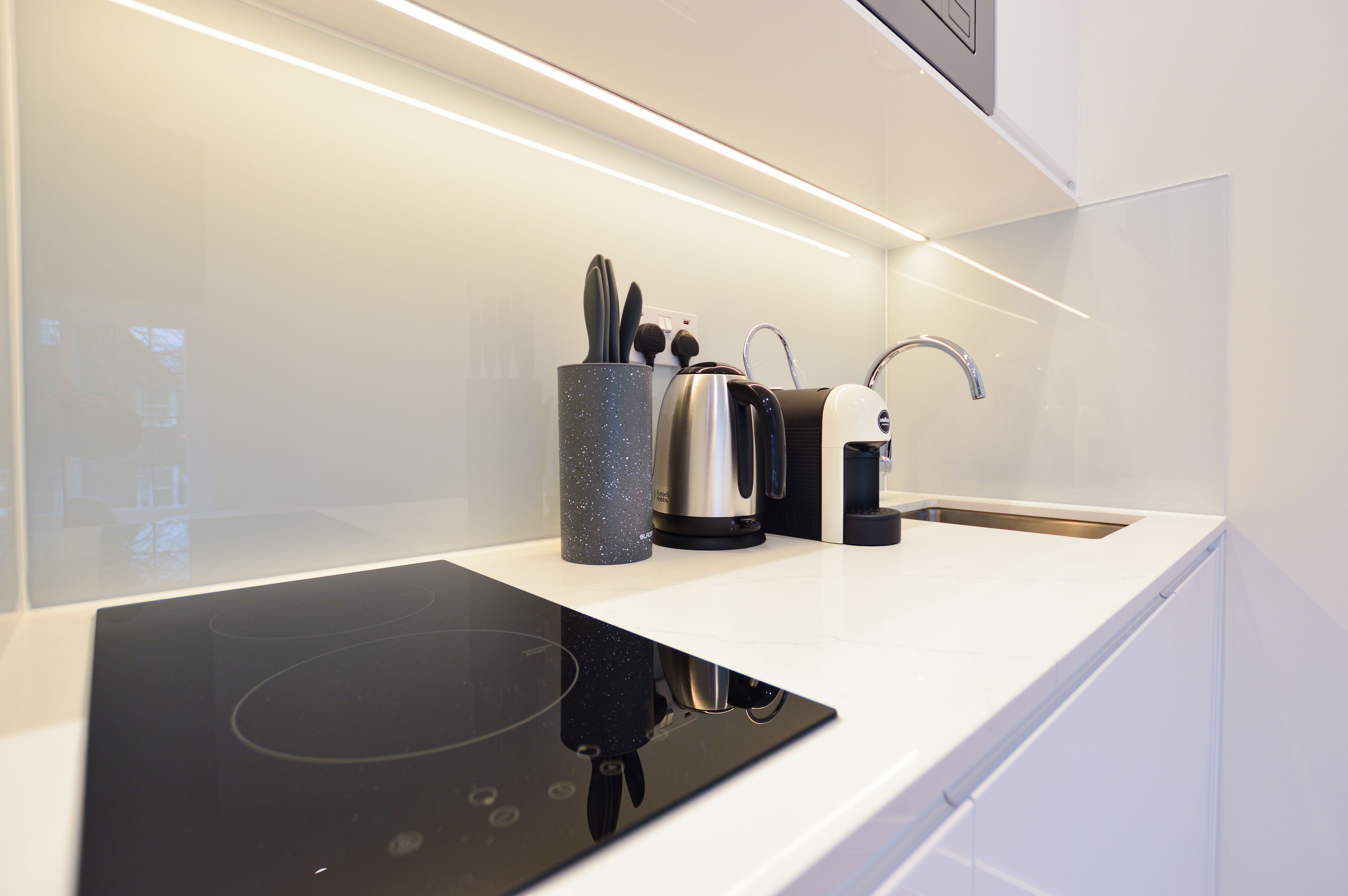 A modern kitchen with a built-in stovetop, a coffee maker, and a kettle.