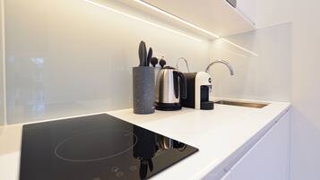 A modern kitchen with a built-in stovetop, a coffee maker, and a kettle.