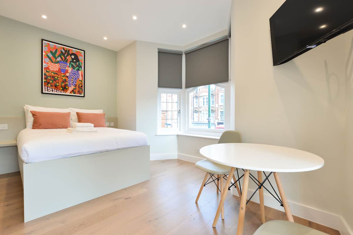 A modern bedroom with a bed, a dining table, and a TV.