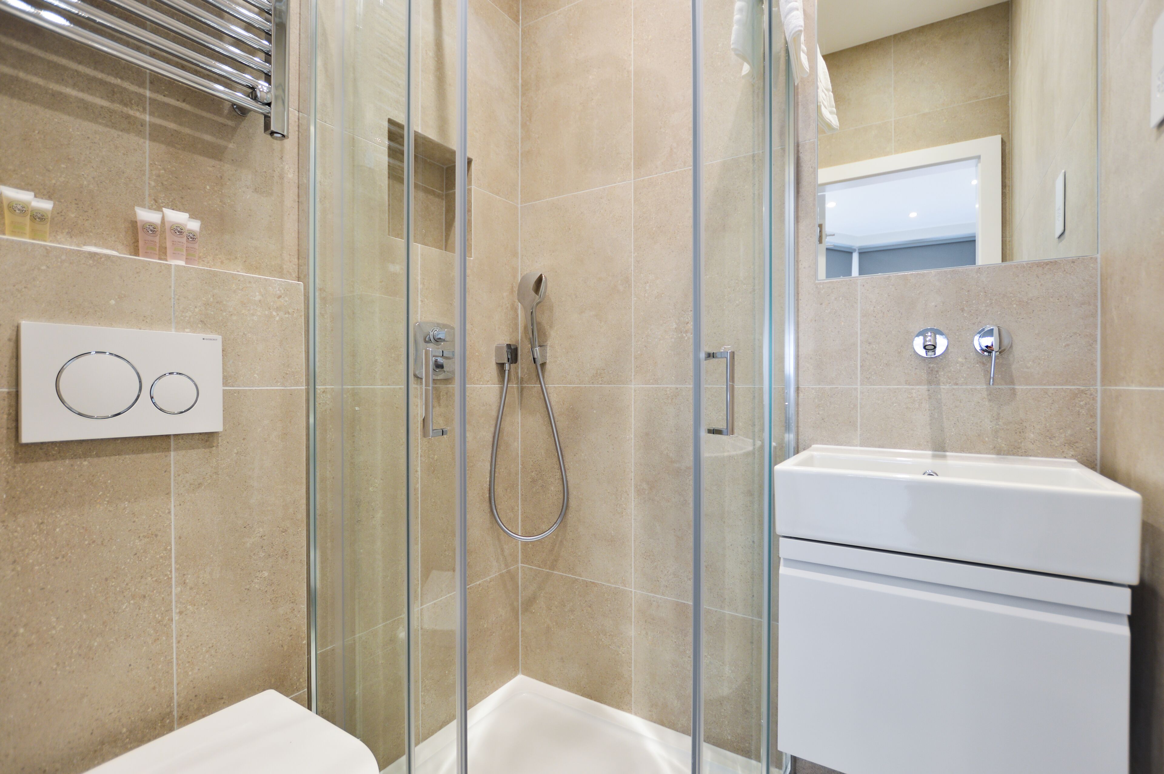 A modern bathroom with a glass-enclosed shower, a white sink, and a mirror.
