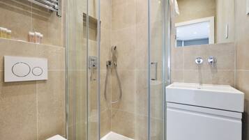 A modern bathroom with a glass-enclosed shower, a white sink, and a mirror.