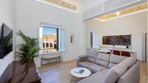 Un salon moderne comprenant un canapé, une table basse, un téléviseur et une grande fenêtre donnant sur un bâtiment historique.