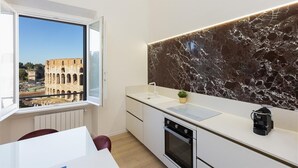 Une cuisine moderne avec un dosseret en marbre, une fenêtre donnant sur un bâtiment ancien et une petite plante posée sur le comptoir.