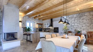 A modern kitchen with stone walls, wooden beams, and a central island. - Charming Villa nestled in a region renowned for its exceptional wineries.  (Triban)