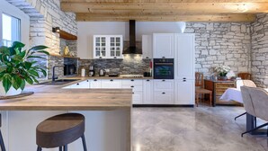 A modern kitchen with stone walls, wooden ceiling beams, and a central island. - Charming Villa nestled in a region renowned for its exceptional wineries.  (Triban)