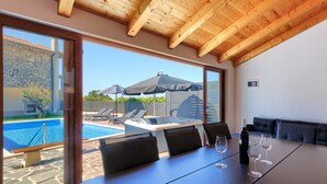 A dining area with a view of a swimming pool and hot tub, wooden ceiling, and a stone wall. - Charming Villa nestled in a region renowned for its exceptional wineries.  (Triban)