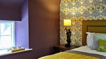 A bedroom with a bed, a nightstand, a lamp, and a window with a view.