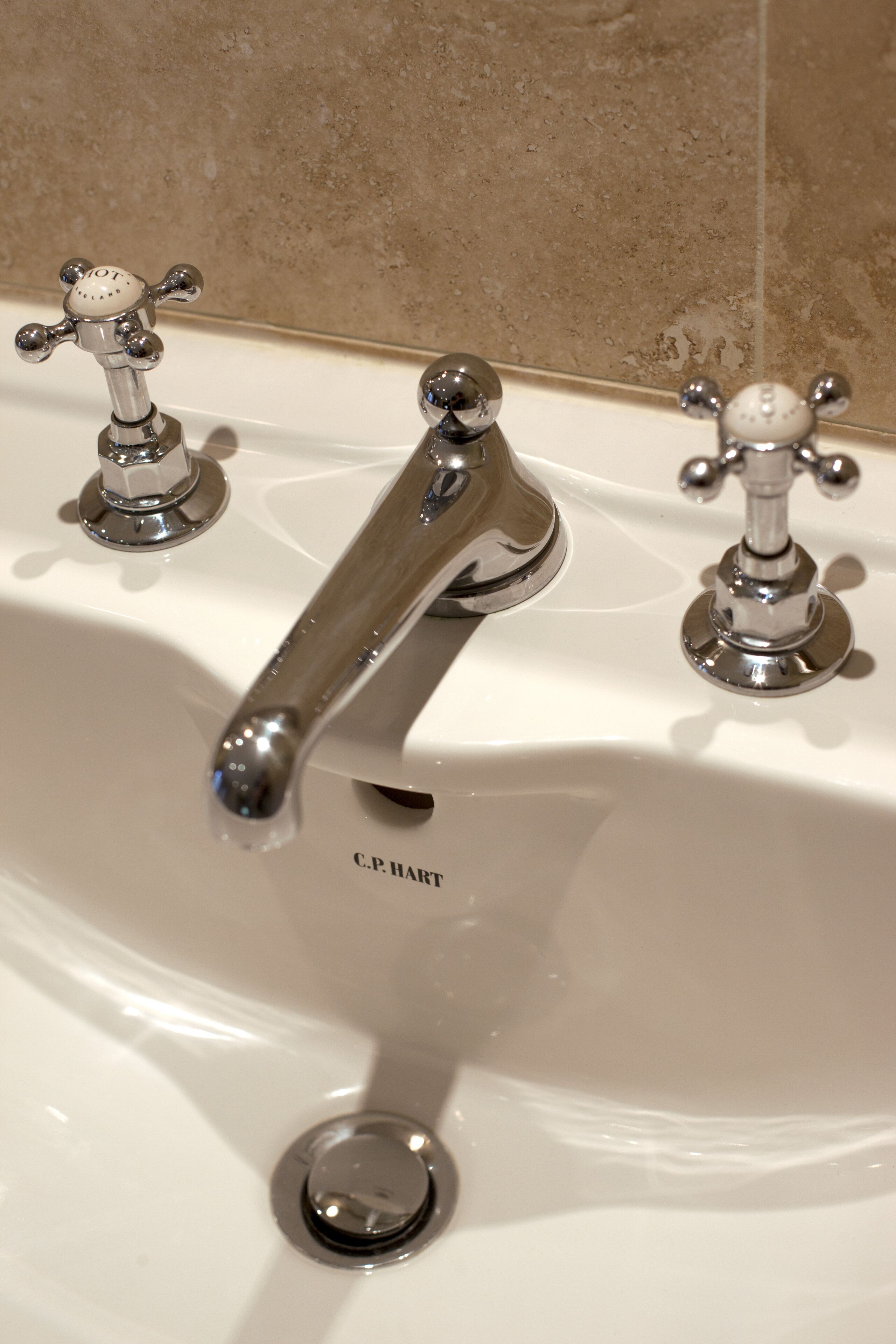 A bathroom sink with two chrome faucets and a drain.
