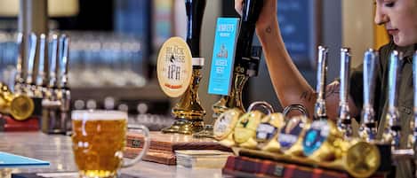 Un bar con varias llaves de cerveza, una jarra de cerveza y una pizarra de menú.