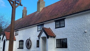 A traditional white building with a red-tiled roof, a large wooden signboard, and a visible chimney. - The Black Horse, Climping (Littlehampton)