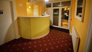 A hotel reception area with a curved counter, a clock above it, and a door labeled "Fire door only." - Station Hotel (Norwich)