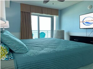 A hotel room with a bed, a window with curtains, a chair, a TV, and a fireplace. - Huge Breathtaking Oceanfront Condo, Beautiful Decor, Drive to the 4th Floor Deck (Myrtle Beach)