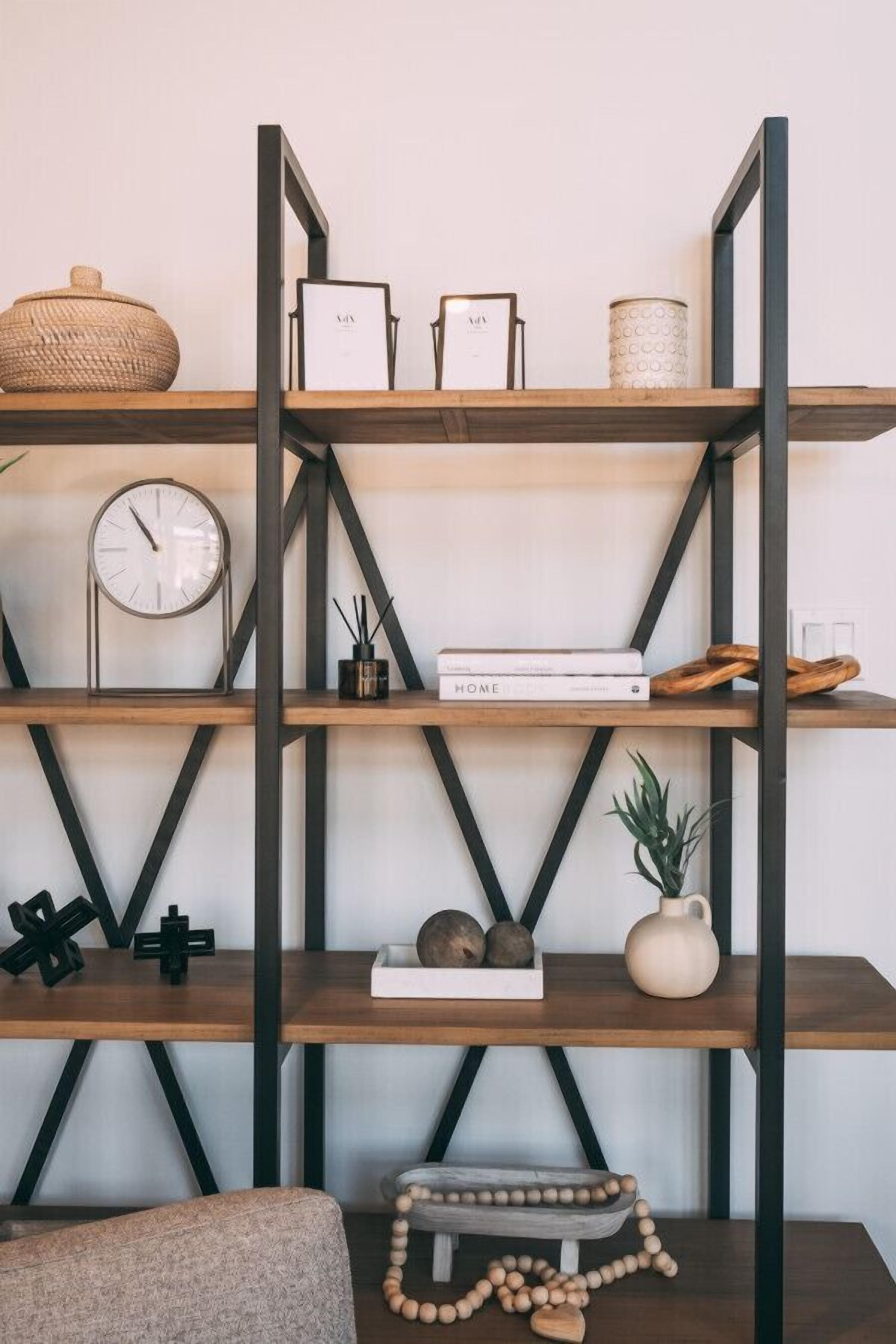 Une étagère en bois à plusieurs niveaux, agrémentée de divers objets décoratifs, notamment une horloge, des livres et un panier tressé.