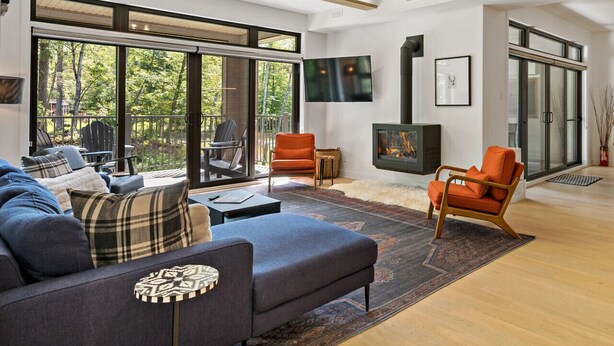 A modern living room with a large sofa, a fireplace, and a television. - Tremblant Prestige - Verbier 12-101 (Mont-Tremblant)