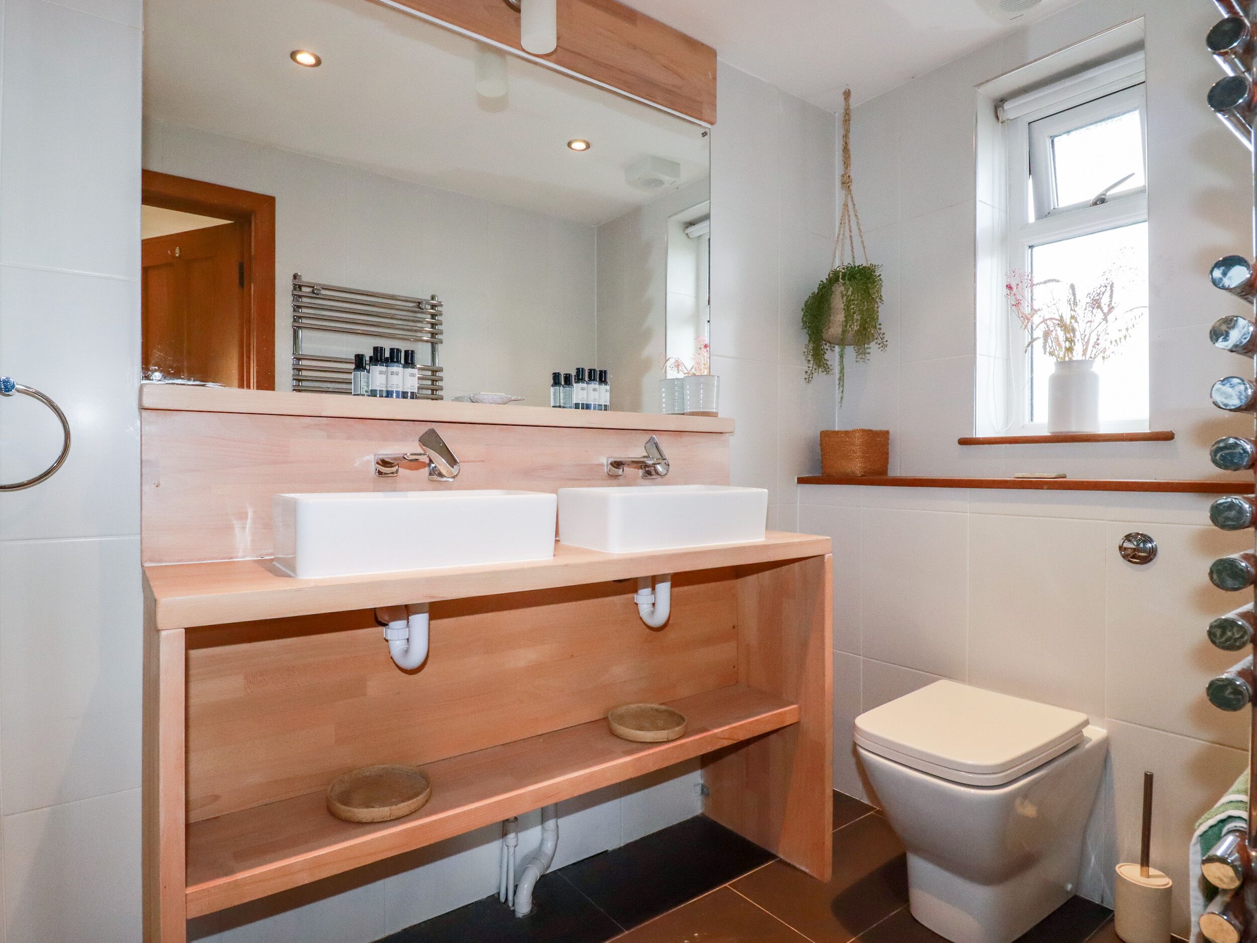 A bathroom with two sinks, a toilet, and a window.