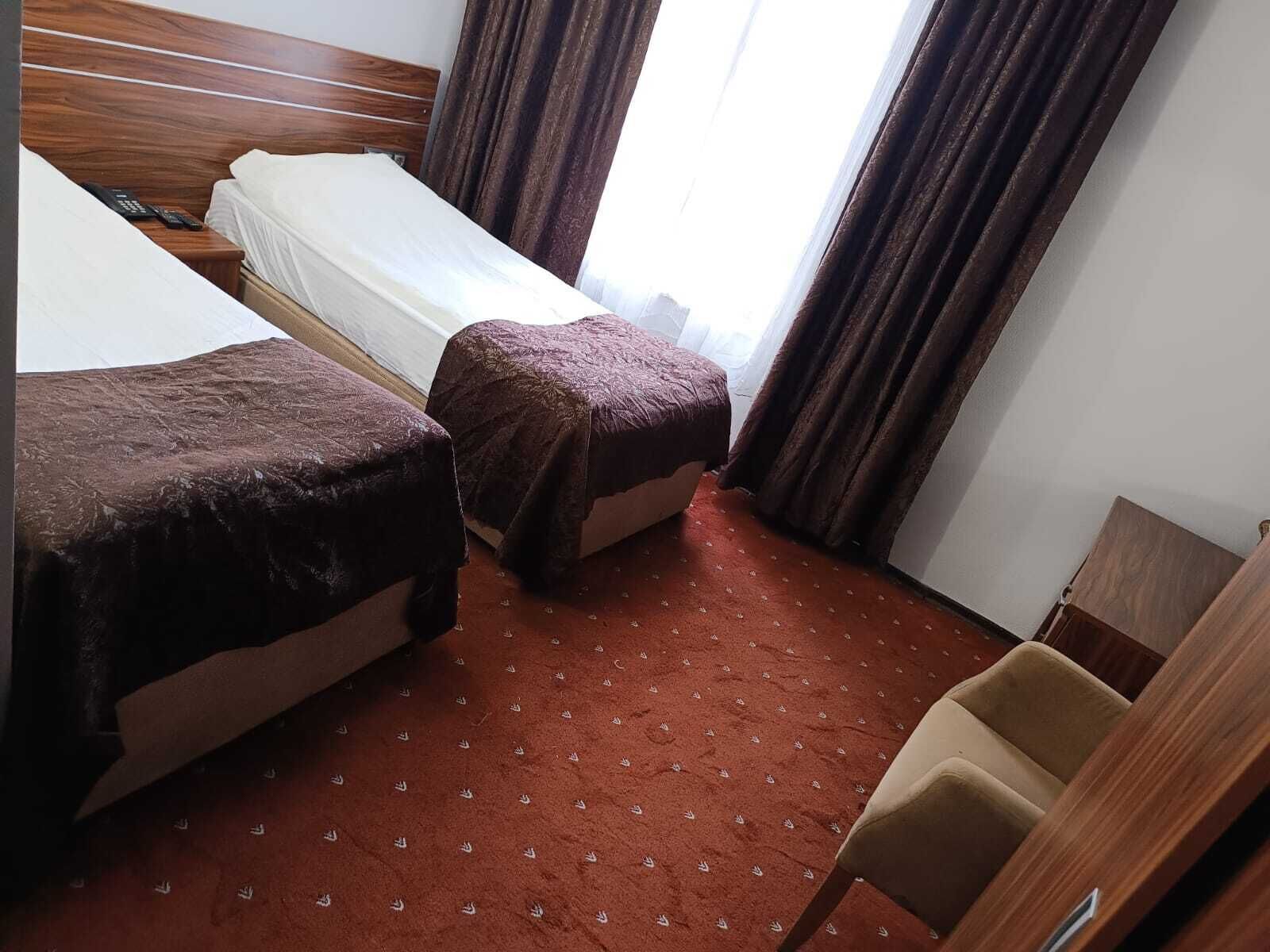 Een hotelkamer met twee bedden, een houten hoofdbord, een klein houten bureau en een stoel.