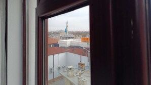 Vista desde una ventana que muestra un edificio con un minarete alto y cúpulas.