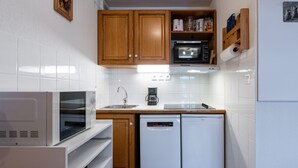 Una cocina compacta con armarios de madera, un microondas, una cafetera y un lavavajillas.
