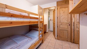 Una habitación pequeña y funcional con literas y una puerta de madera.
