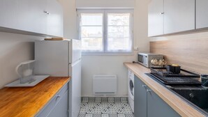 A compact kitchen with a wooden countertop, a washing machine, a microwave, and a window with blinds. - Mélodie - Bel appartement vue mer (Criel-sur-Mer)