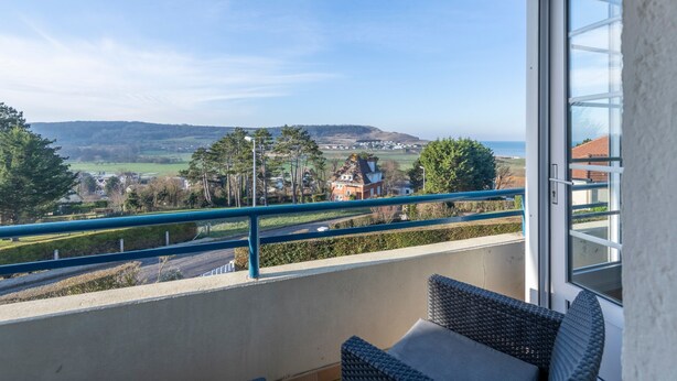 A balcony with a view of a rural landscape, a wicker chair, and a glass door. - Mélodie - Bel appartement vue mer (Criel-sur-Mer)