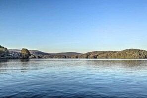 Um lago tranquilo com uma casa à esquerda e colinas ao fundo.