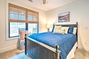 Ein Schlafzimmer mit einem großen Bett, einem Fenster mit Jalousien, einem Nachttisch und einer Wandlampe.